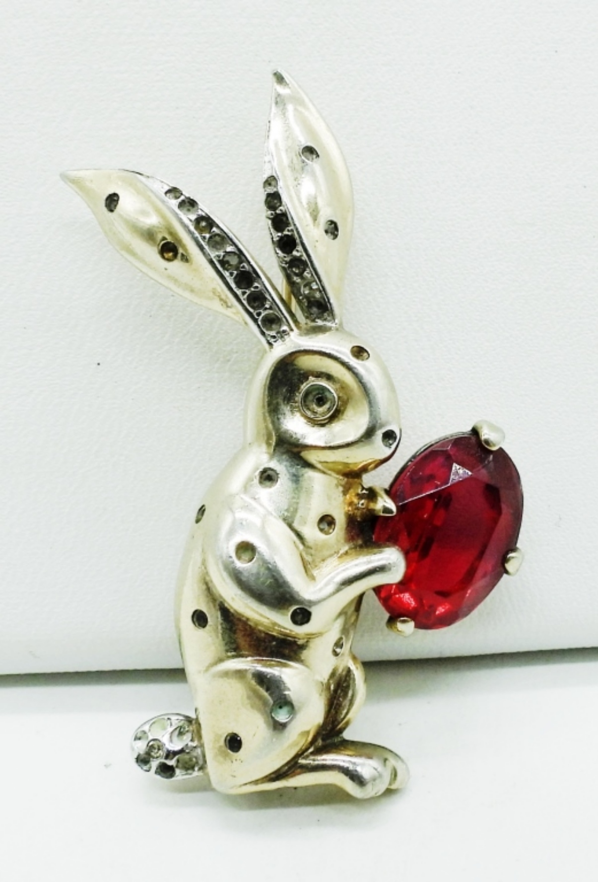 Sterling silver rabbit trinket holding a large red gemstone, with black accents on its ears.
