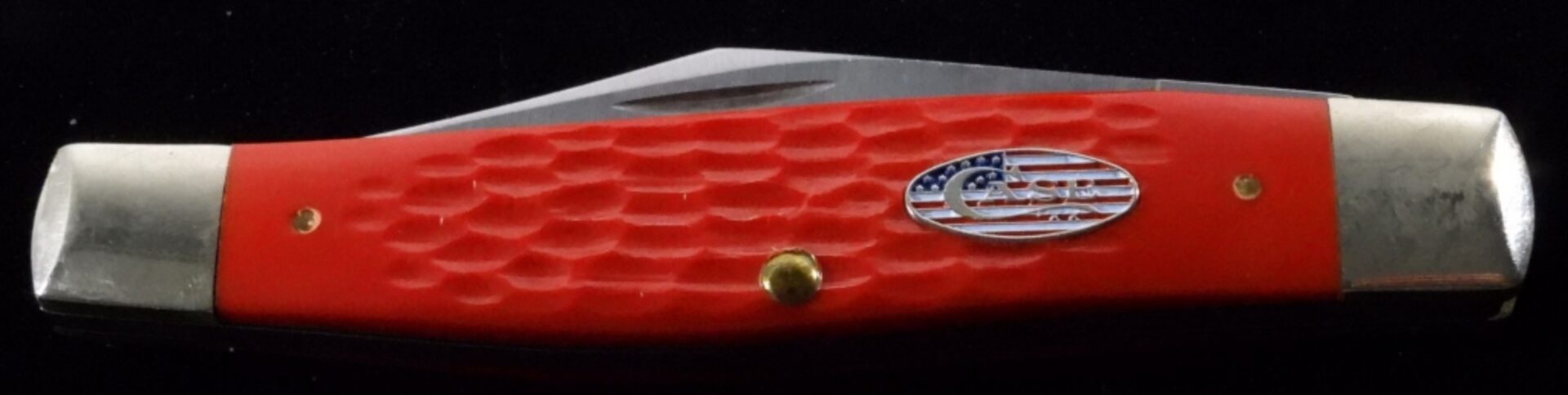 Red-handled pocket knife with American flag emblem featured in lighters and knives auction.