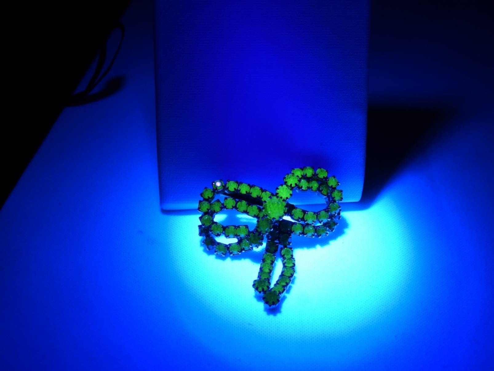 Uranium glass brooch glowing under UV light, featured in our costume jewelry auction.